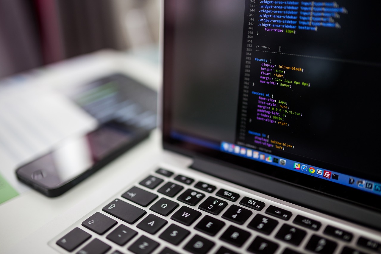 A laptop showing CSS code in an editor next to a smartphone on a desk