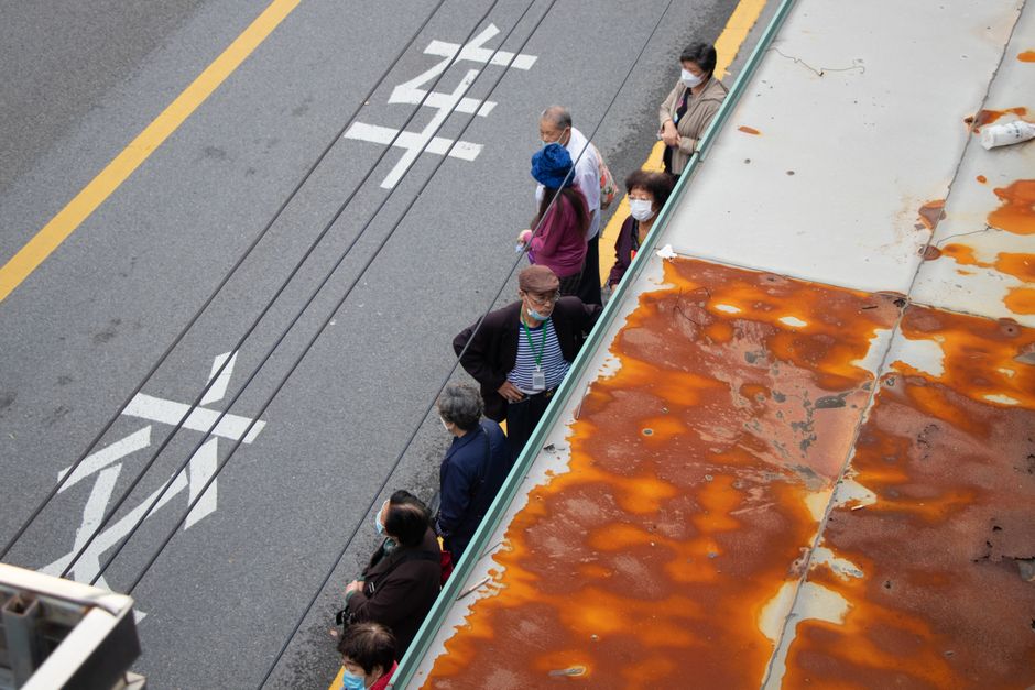 People queuing along a kerb, seen from above, with road markings on the tarmac beside them. A render-blocking script does the same thing to the parser: everything behind it waits, in order, until the one at the front is finished.