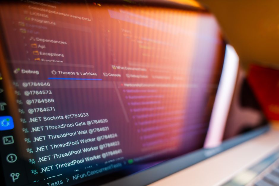 Nahaufnahme eines Laptop-Bildschirms mit dem Debug-Panel eines Code-Editors, einem Reiter Threads and Variables und einer Liste von .NET-Threadpool-Threads. Das Foto zeigt eine .NET-Debugging-Sitzung, nicht Vue.