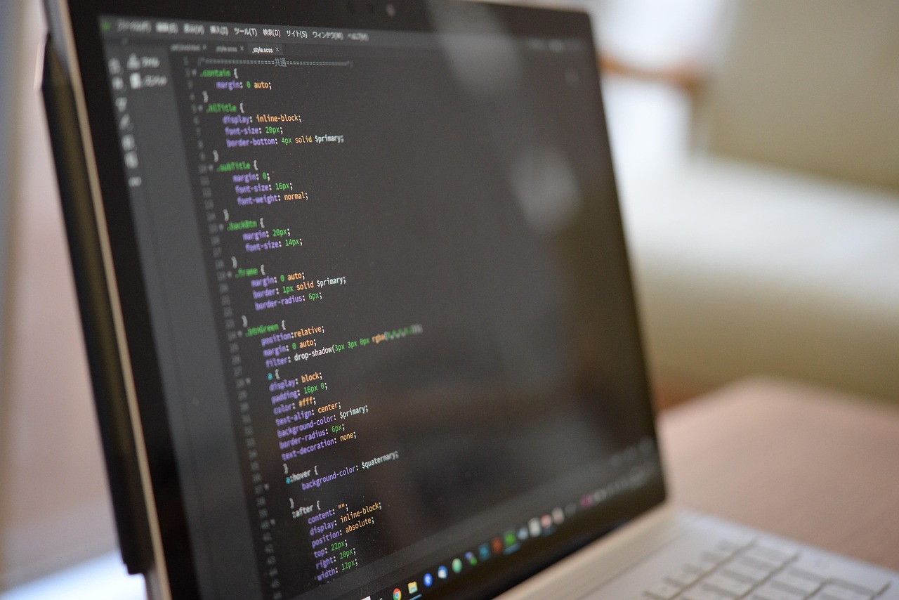 A laptop displaying SCSS and CSS source code in an editor