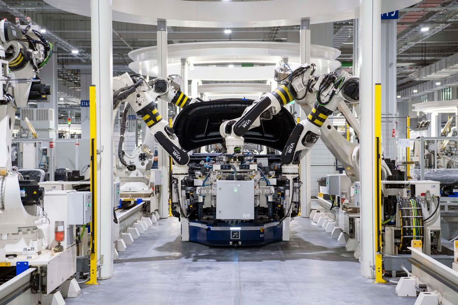 Bracci robotici che assemblano la scocca di un veicolo in una fabbrica automatizzata