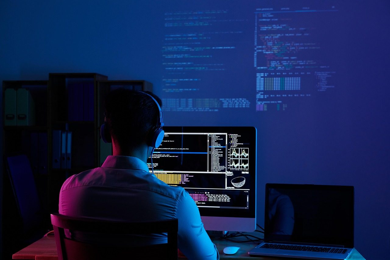 Un développeur travaillant à un ordinateur avec du code à l'écran.