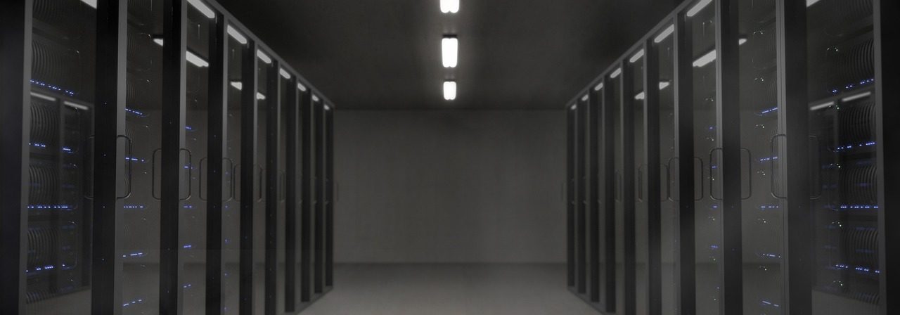 A dark server room with rows of equipment and glowing LED lights